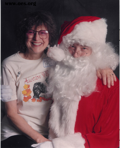 Grannie Annie Raker, Placement Director for New England Old English Sheepdog Rescue, Inc. is Sitting on Santas lap.  Both are laughing.